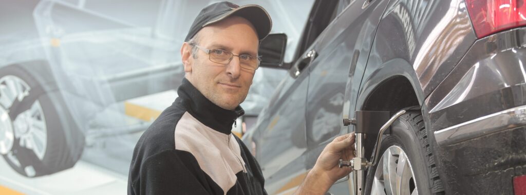 Bilden visar en man som utför byte av däck. För däckbyte i Kalmar med nya däck i Kalmar samt service och reparationer på Peugeot, Citroen och AC verkstad