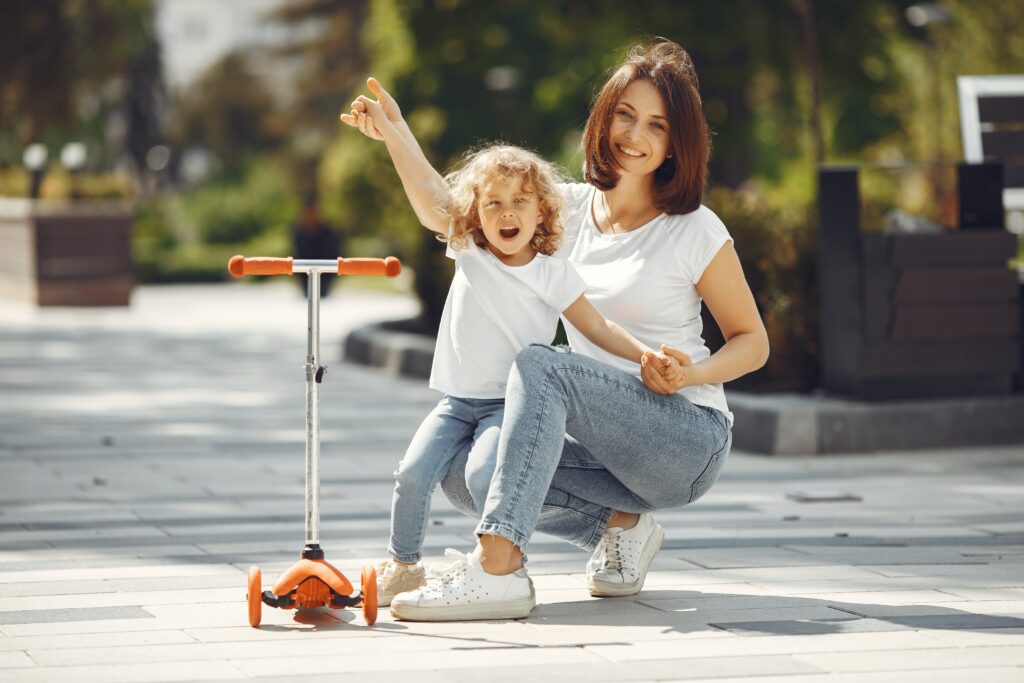 Bilden visar mamma med barn och scooter det finns även praktiska varianter som Puky springcykel och Puky balanscykel skapa roliga utomhuslekar med en studsmatta för barn