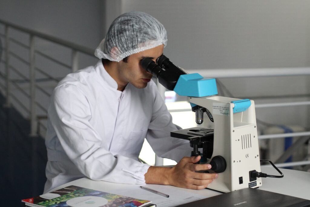 Bilden visar en person på ett laboratorium med ett stillastående arbete. En balansplatta och gummimatta kan bidra till en bättre ergonomi.