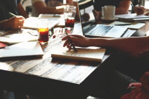 Bilden visar en grupp människor i möte. Ledarskapsutbildning UGL betyder Utveckling av Grupp och Ledare som är en ledarskapsutbildning.